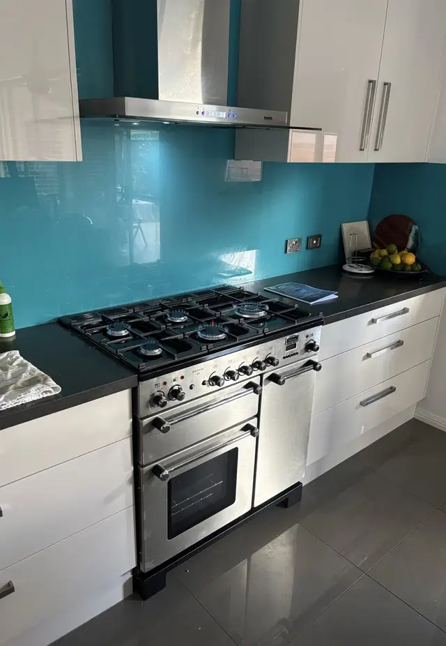 Freestanding stainless steel gas cooker installed in a kitchen, with all burners lit